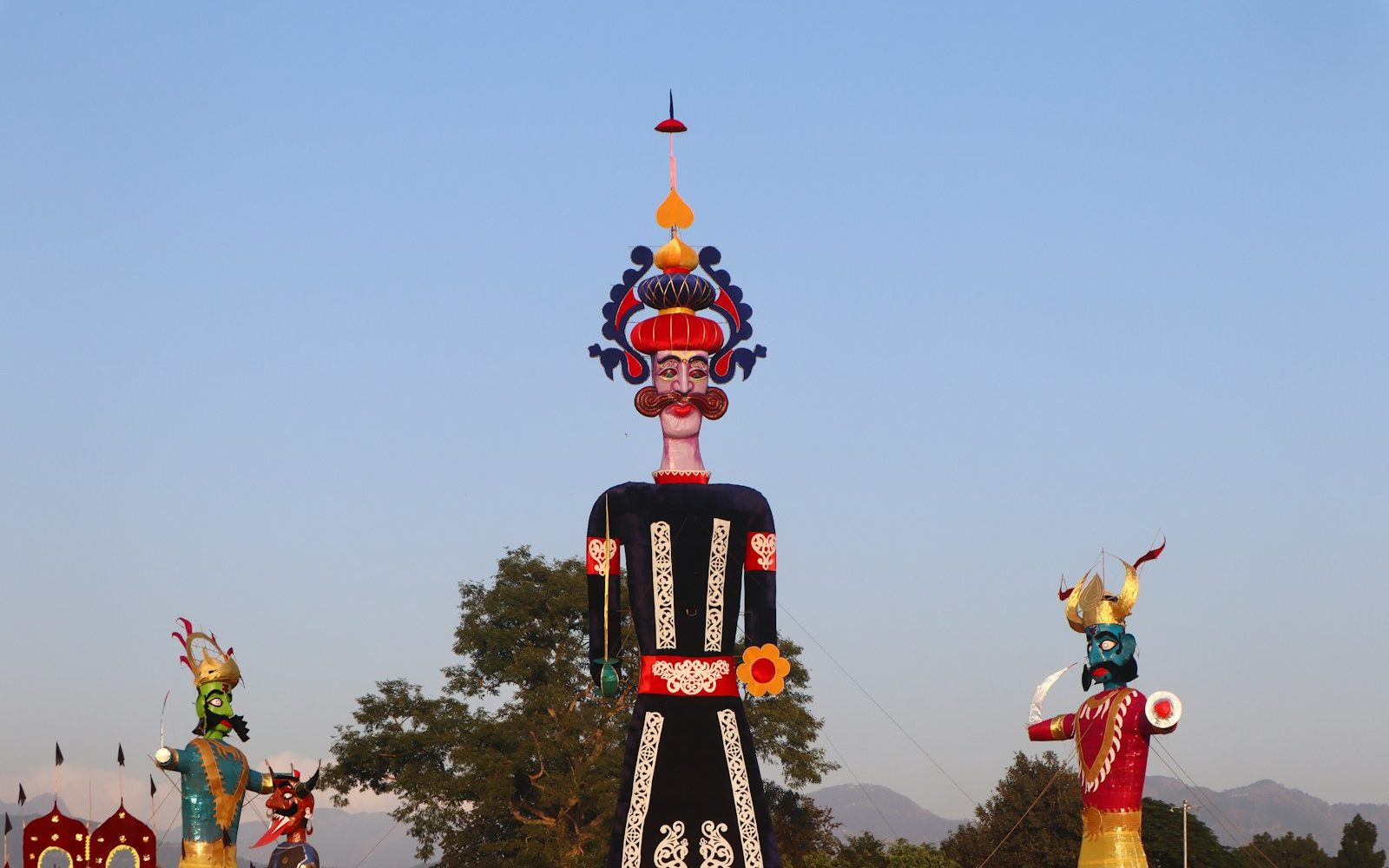 Tall painted effigies of Ravana standing against a blue sky before Dussehra