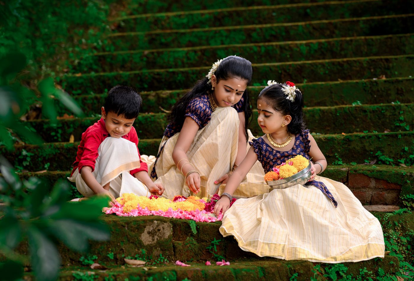 Children in traditional Kerala attire making a Pookalam for Onam